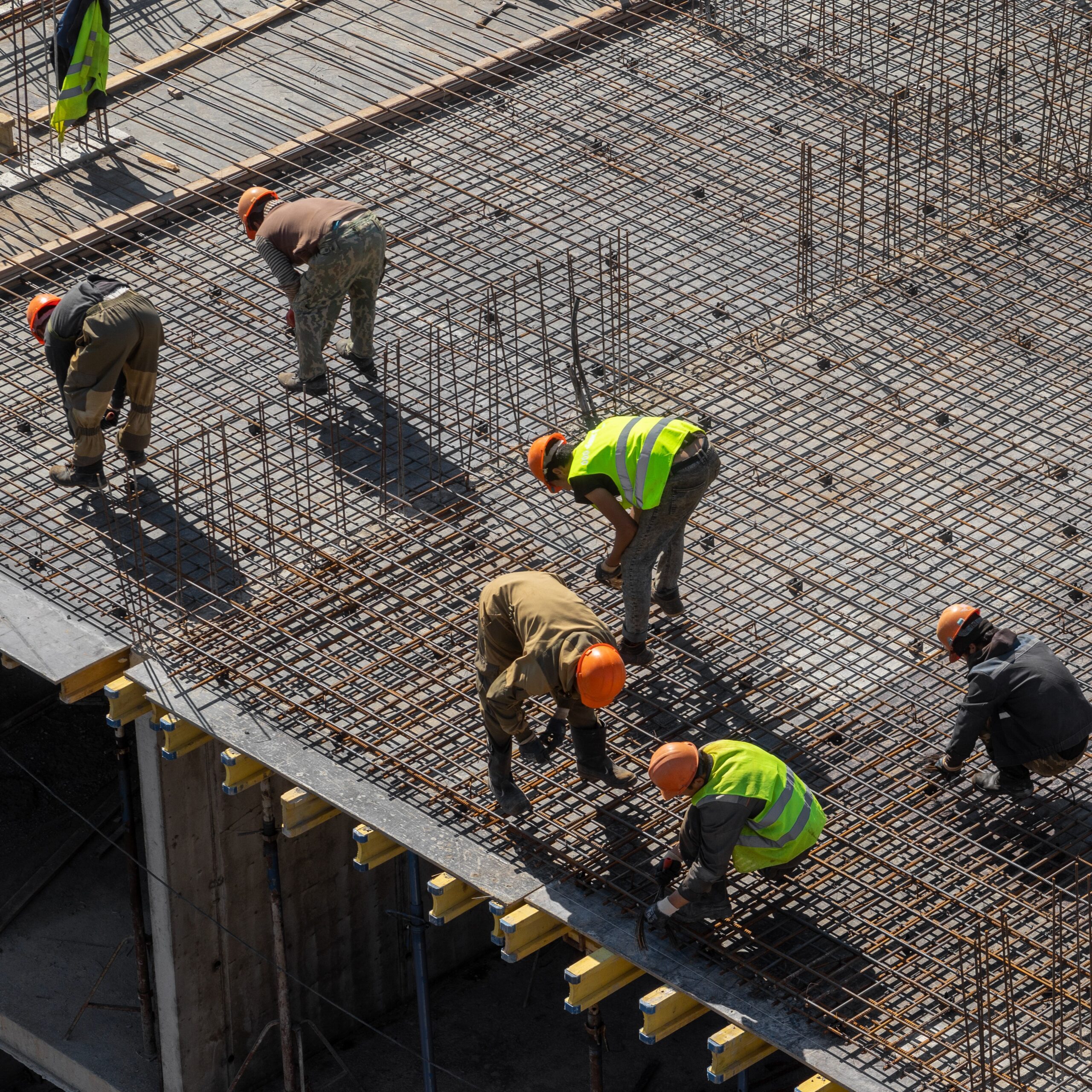 builders in hard hats and protective vests work at the construction site of a multi-storey building